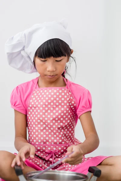 Aziatisch kind spelen een chef-kok thuis. — Stockfoto