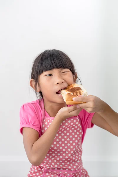 家でパンを食べるアジアの女の子. — ストック写真