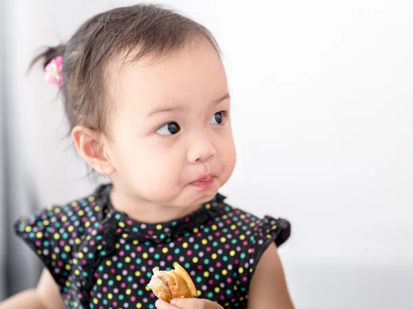 Asiatisk Tjej äter bröd hemma. — Stockfoto