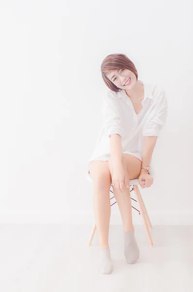 Attraktiva asiatisk tjej sitter på vit modern stol och koppla av på — Stockfoto