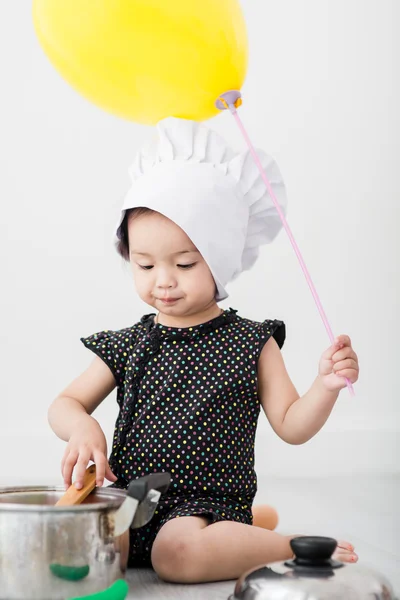 Asijské dítě hraje kuchař ruka držení balónu doma. — Stock fotografie