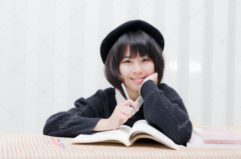 Cute Asian teenager student reading at home.