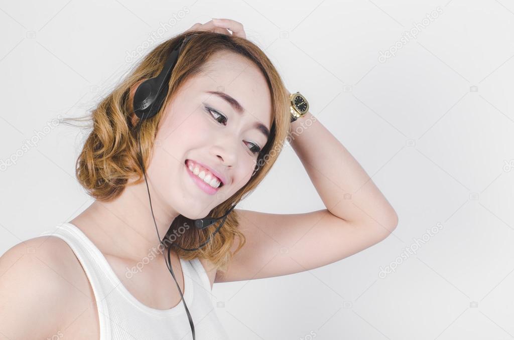 Happy Asian woman using headphone listening music on gray backgr