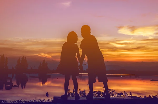 Broer en zus hand in hand samen met zonsondergang. — Stockfoto