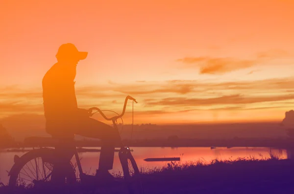 Silhueta Cycler no nascer do sol contra o sol céu nublado — Fotografia de Stock