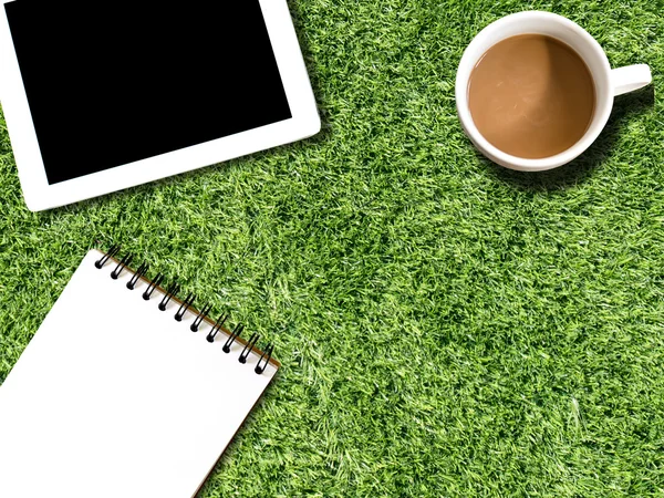 Tablet, xícara de café em grama artificial campo paisagem vista — Fotografia de Stock
