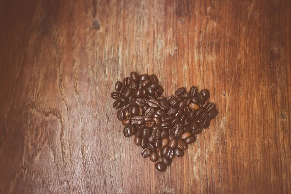 Σχήμα καρδιάς από κόκκους καφέ σε ξύλινη επιφάνεια. — Φωτογραφία Αρχείου