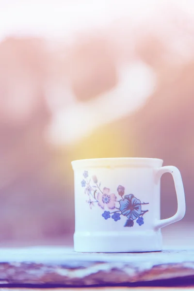 Weiße Kaffeetasse mit schneebedecktem Hintergrund. Vintage-Ton. — Stockfoto