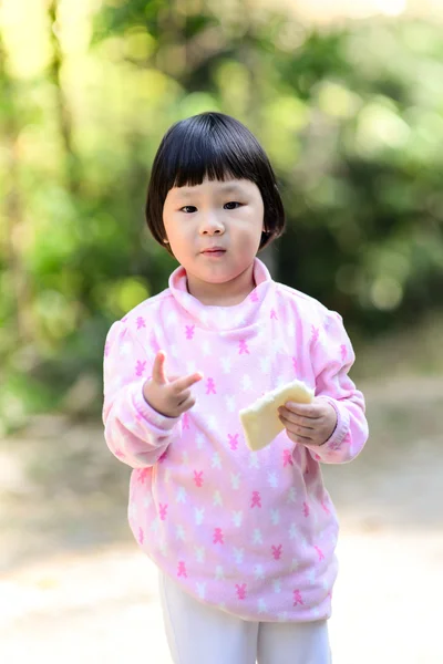 Wenig asiatische Mädchen essen Brot im Freien. — Stockfoto