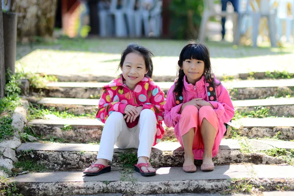 Glada asiatiska tjejer i tröja sitter i parken utomhus. — Stockfoto