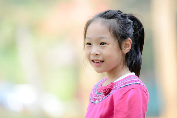 Glücklich asiatische Mädchen tragen rosa Pullover und lächeln mit Bokeh ba — Stockfoto