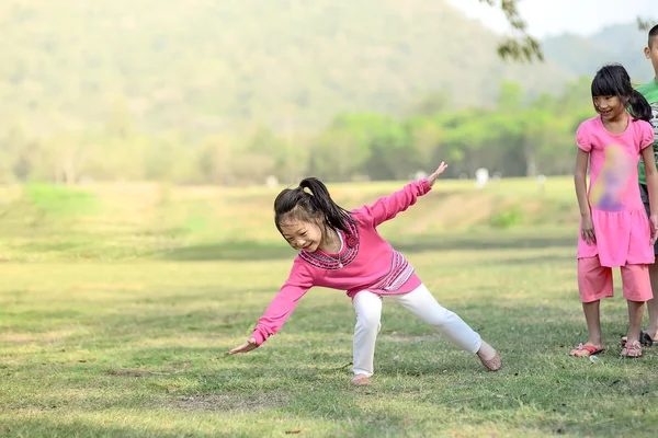 Little beautiful girl somersaults on green field with her friend — Stock Photo, Image