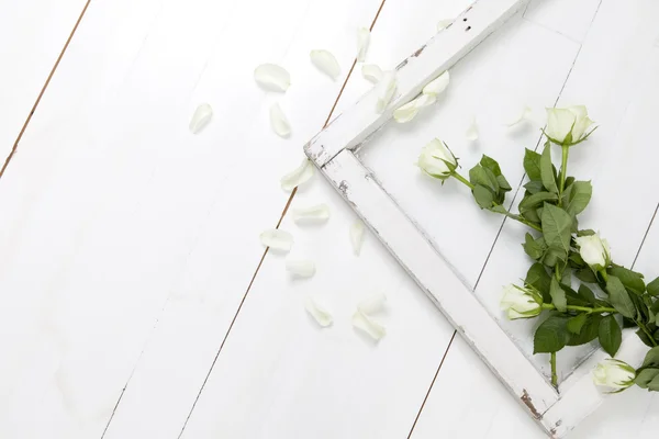 Fünf weiße Rosen, abgefallene Blütenblätter und altes rustikales Fenster auf weißem Holzboden — Stockfoto
