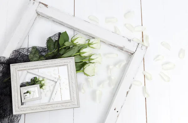 Bilderrahmen mit weißen Rosen, abgefallenen Blütenblättern und schwarzer Spitze Stockfoto