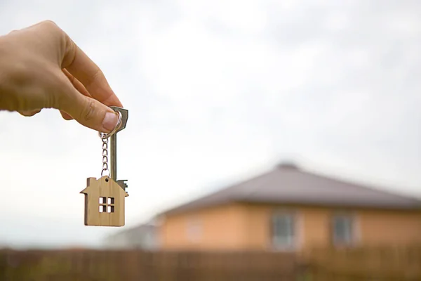 Hand Mit Einem Schlüssel Und Einem Schlüsselanhänger Aus Holz Hintergrund — Stockfoto