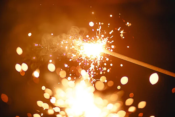 Karanlıktaki kıvılcımlardan kıvılcımlar ve ışık parlak sarı ve turuncu bokeh ve duman. Şenlikli ateş dokusu, yeni yıl ve Noel için arka plan.