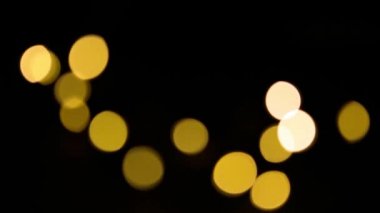 Sarı ve altın renkli çelenkler siyah arka planda bulanık. Bokeh of fly circle in the defocus. Noel ve yeni yılın şenlikli atmosferi. Arkaplanı kutla