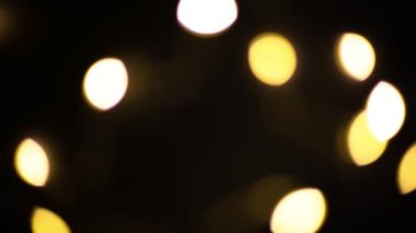 Sarı ve altın renkli çelenkler siyah arka planda bulanık. Bokeh of fly circle in the defocus. Noel ve yeni yılın şenlikli atmosferi. Arkaplanı kutla