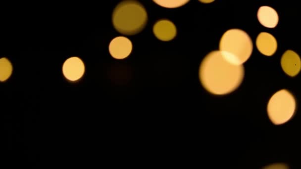 黄色和金色的灯光在黑色的背景上模糊地装饰着 在脱焦状态下飞行圈的波克 圣诞和新年的喜庆气氛 庆祝背景 — 图库视频影像
