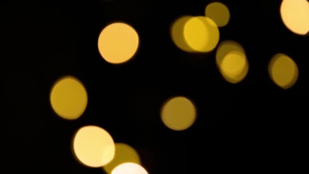 黄色和金色的灯光在黑色的背景上模糊地装饰着 在脱焦状态下飞行圈的波克 圣诞和新年的喜庆气氛 庆祝背景 — 图库视频影像