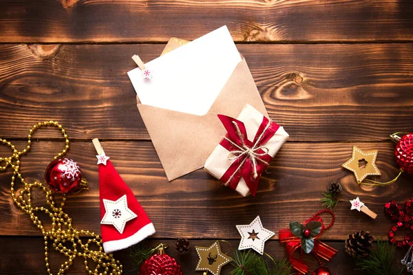 クリスマスの装飾と木製の背景にテキストのための白いシートとクラフト紙で作られたメール封筒 サンタクロースへの手紙 願い事リスト 新年の夢 贈り物 コピースペース — ストック写真