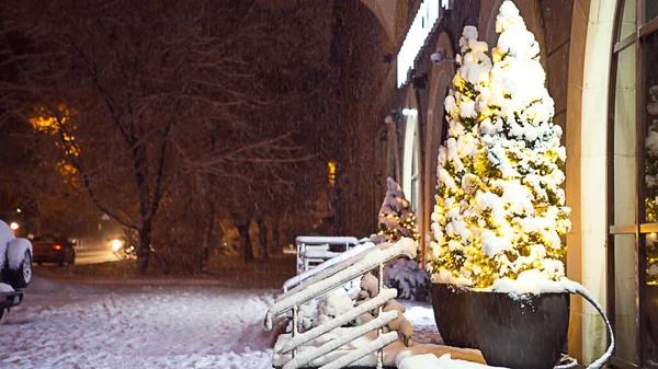 圣诞前夜降雪中的夜市街道 装饰着圣诞装饰品 圣诞树 闪闪发光的花环 楼梯和栏杆上都是雪 — 图库照片