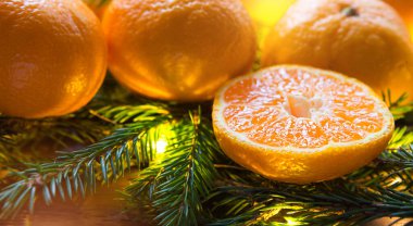 Çelenk ışığında taze mandallar, köknar dalları ve süslemeler. Yeni yılın parlak arkaplanı. Yarım portakal, turunçgil aromalı bayram. Noel, yeni yıl. Metin için boşluk.