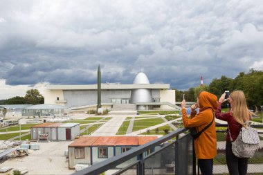 Rusya, Kaluga, 14 Ağustos 2020. Kaluga Kozmonotlar Müzesi. Turistler çekim yerinin telefonunda fotoğraf çekiyorlar. Roket, gökevi kubbesi, yeniden yapılanma, ikinci hattın inşaatı.