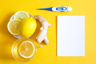 Bir fincanda tıbbi çay, zencefil, soğuk mevsimde bağışıklık sistemini limon güçlendirme, termometre ve fotokopi alanı, notlar için çarşaf. Sarı arka planda sağlık ve malzemeler için vitamin içeceği. 