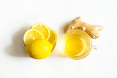 Bir fincanda tıbbi çay, zencefil, soğuk mevsimde bağışıklık sistemini limon güçlendirir. Beyaz arka planda sağlık ve malzemeler için vitamin içeceği.