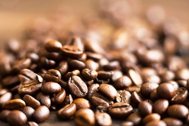 Kavrulmuş kahve çekirdekleri. Arka planda güzel kokulu. Kahverengi Arap kahve çekirdekleri ahşap masaya saçılmış. Boşluğu kopyala