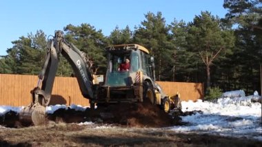 Buldozer kovası inşaat için bir çukur kazıyor. Evin temeli, toprak işleri. Kazıcı bir kova ile toprağı kazar. Kaluga, Rusya, 30 Mart 2021