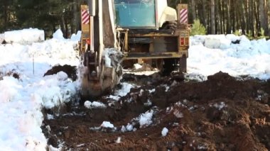 Buldozer kovası inşaat için bir çukur kazıyor. Evin temeli, toprak işleri. Kazıcı bir kova ile toprağı kazar. Kaluga, Rusya, 30 Mart 2021