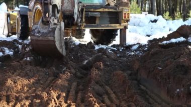 Buldozer kovası inşaat için bir çukur kazıyor. Evin temeli, toprak işleri. Kazıcı bir kovayla toprağı kazar..