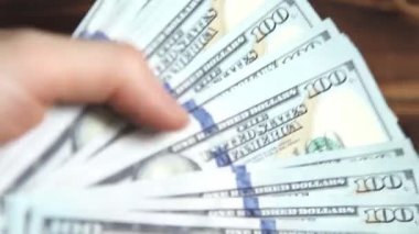 Kadınların elleri parayı sayar: Tahta bir masaya dolar koyar, banknotları çevirirler. Yüz dolar. Yakın plan 100 dolarlık banknotlar. Finans, ekonomi, mali planlama, ekonomi, tasarruflar.