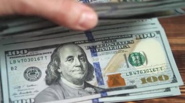 Kadınların elleri parayı sayar: Tahta bir masaya dolar koyar, banknotları çevirirler. Yüz dolar. Yakın plan 100 dolarlık banknotlar. Finans, ekonomi, mali planlama, ekonomi, tasarruflar.