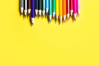 Sarı arka planda renkli kalemler var. Kopyalama alanı, çerçeve. Okula dönüyorum, ressam, resim dersleri alıyorum. Yaratıcılık için kırtasiye, çiz