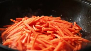 Aşçı tavaya dilimlenmiş havuç, et parçaları ve sosta sotelenmiş soğan koyar ve sotelenmiş kaşıkla karıştırır. Dökme demir kazanda pilav pişirmek, zirvak, doğu mutfağı. Sekizinci adımda.