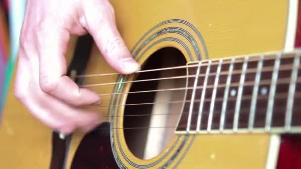 ギターの板の上の男の手は弦を通して指を動かし コードをクランプします インストゥルメンタル音楽 シート音楽のギターレッスン — ストック動画