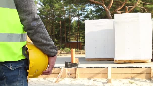 Byggarens Hand Håller Gul Skyddshatt Byggarbetsplatsen Med Husets Grund Träform — Stockvideo