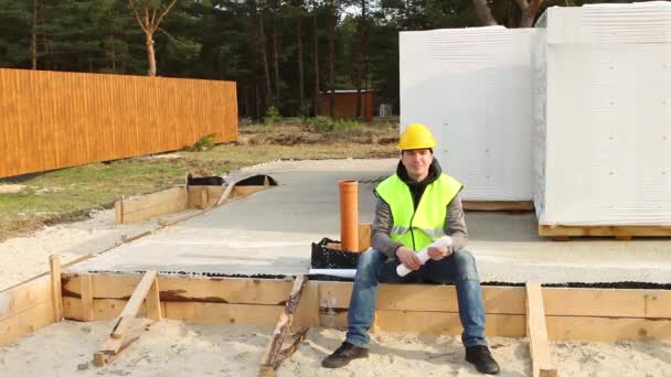 Ein Bauarbeiter Mit Gelbem Schutzhelm Und Signalweste Setzt Sich Auf — Stockvideo