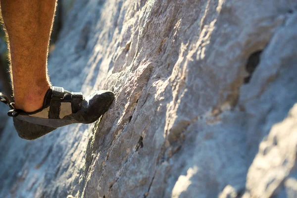 Climbing shoes on the climber\'s foot rest the toe on the rock. Extreme sports, mountain tourism. Close-up. Copy space. Hairy male leg