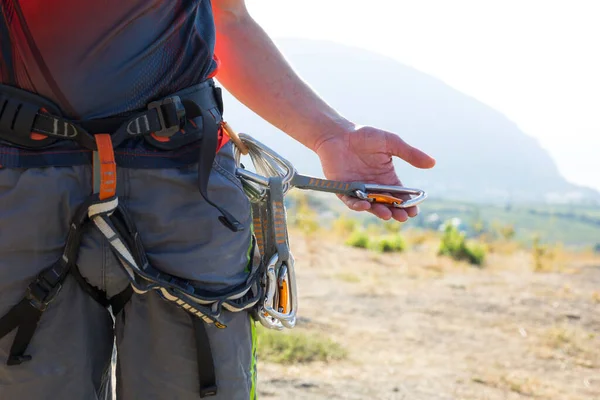 Climbing equipment on a male climber: rock shoes, rope, quickdraw, safety device, harness. Sports mountain tourism, active lifestyle, extreme sports
