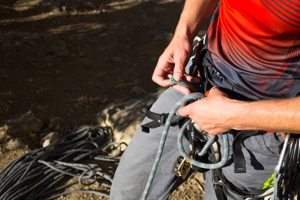 A male climber ties a safety knot eight on the harness before climbing the track. Climbing equipment: rope, quickdraw, safety device, harness. Sports mountain tourism, active lifestyle, extreme sports