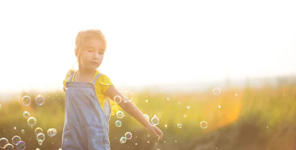 Дівчинка Денімському Костюмі Підриває Мильні Бульбашки Влітку Полі Заході Сонця — стокове фото