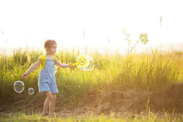 Una Chica Mono Mezclilla Sopla Burbujas Jabón Verano Campo Atardecer — Foto de Stock