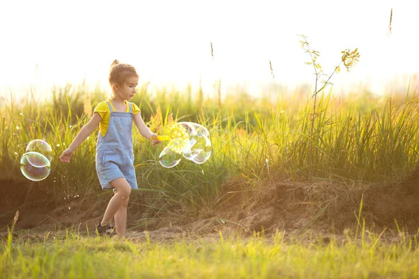 Girl Denim Jumpsuit Blows Soap Bubbles Summer Field Sunset International — Stock Photo, Image