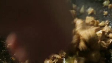 Aşçının elinde slotlu bir kaşıkla, soğanlı et parçaları karıştırılıyor. Yağ, dökme demir tavada kızartılıyor. Buhar geliyor, yağ kaynıyor. Et güveci, kazanda barbekü, yakın plan.