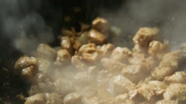 Soğanlı et parçaları dökme demir bir tavada yağda kızartılıyor. Yuvarlak tabanlı, buhar geliyor, yağ kaynıyor. Kazanda et güveci pişiriyorum, yakın plan.