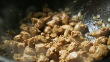 Soğanlı et parçaları dökme demir bir tavada yağda kızartılıyor. Yuvarlak tabanlı, buhar geliyor, yağ kaynıyor. Kazanda et güveci pişiriyorum, yakın plan.